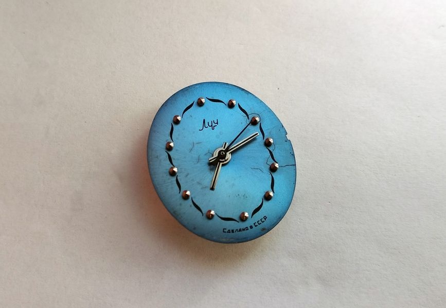 Luch 1809 movement out of its case, dial up, showing a cracked and stained blue dial