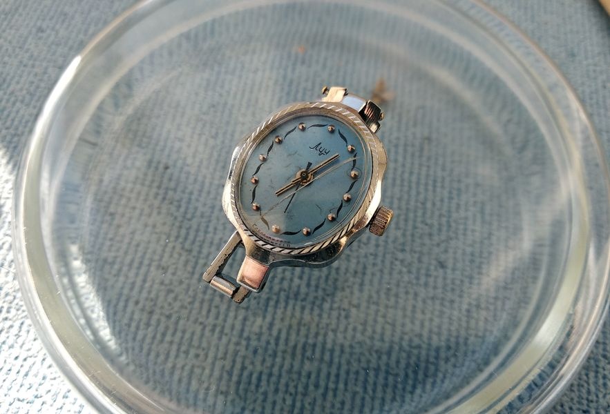 Ladies' Luch watch as received, lying dial up in a glass dish, with a cracked crystal and worn dial