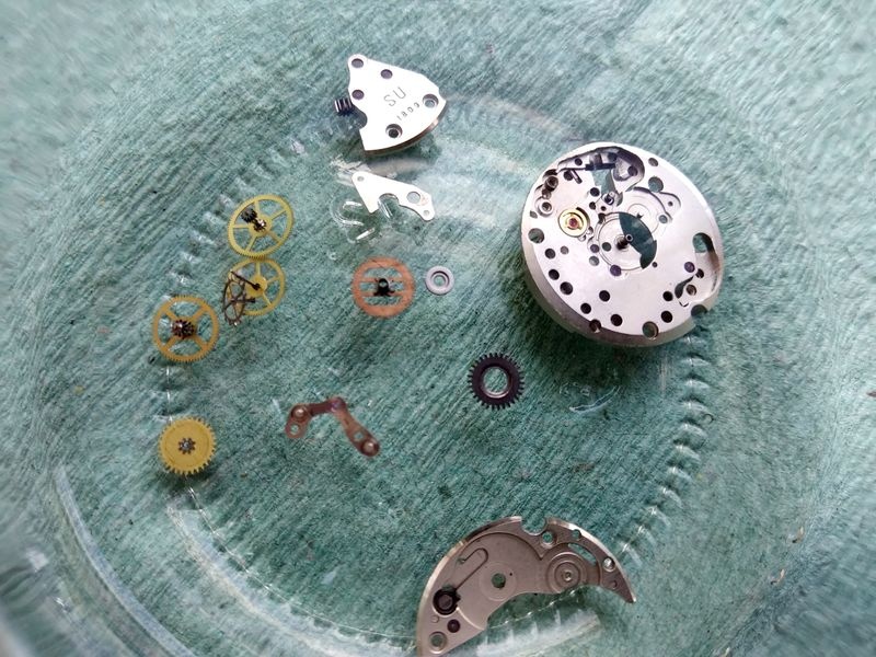 Train wheels, main plate, and bridges of the Luch 1809 in a dish of benzine