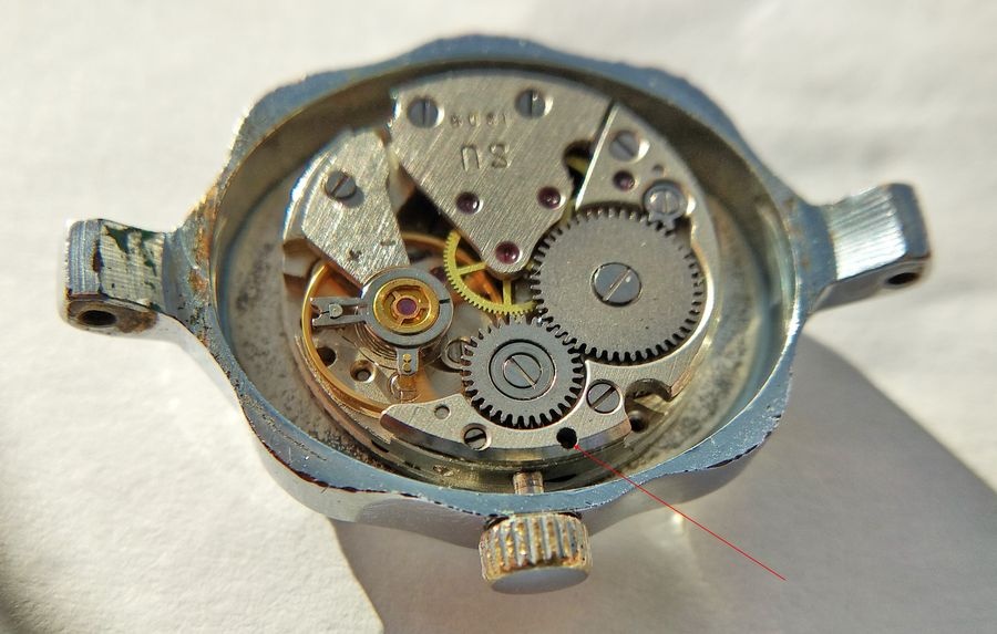 Movement inside the case with a red line pointing to the recessed stem release next to the crown