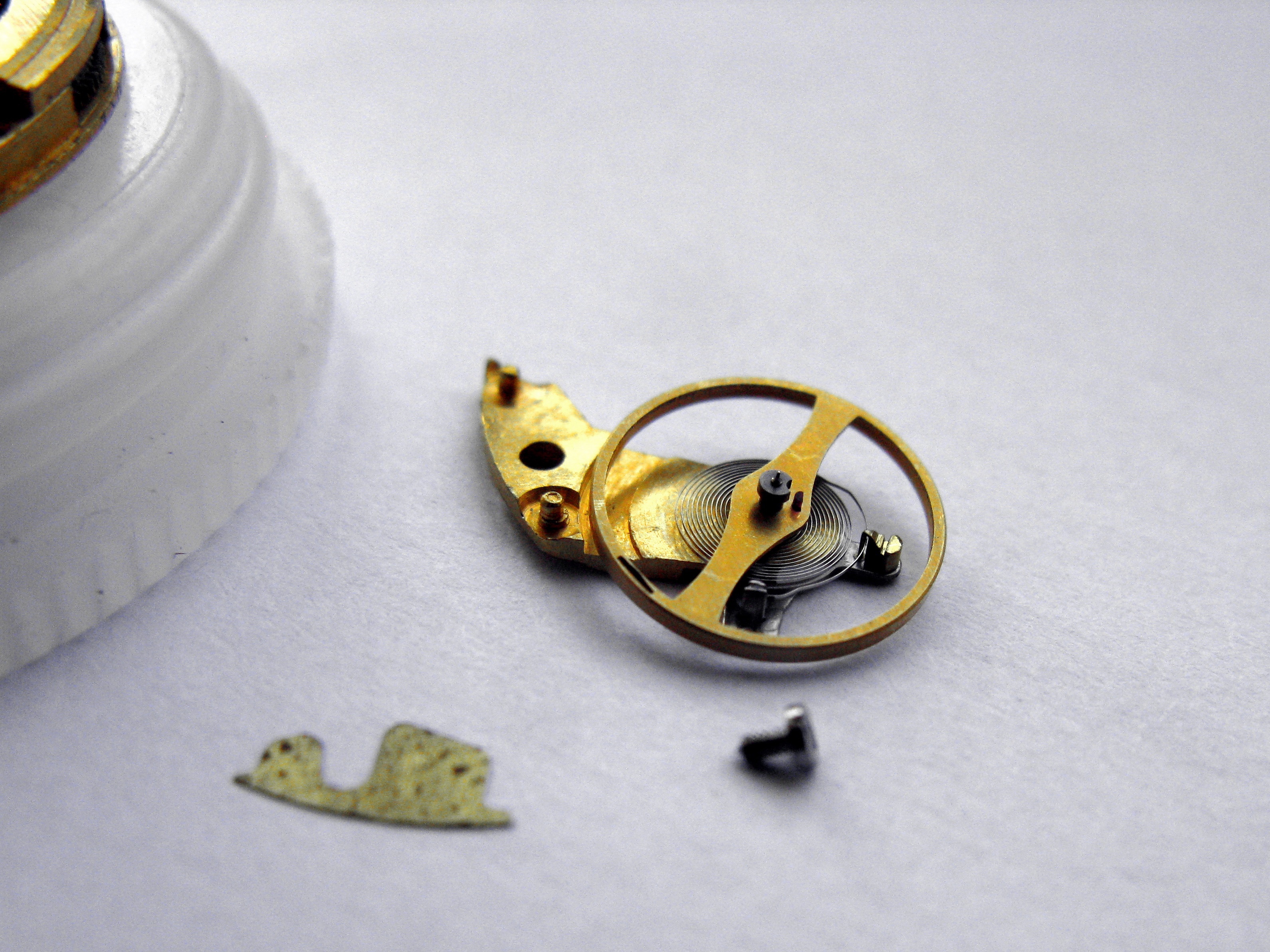 The detached balance turned over to show the flat hairspring coiled beneath the cock.