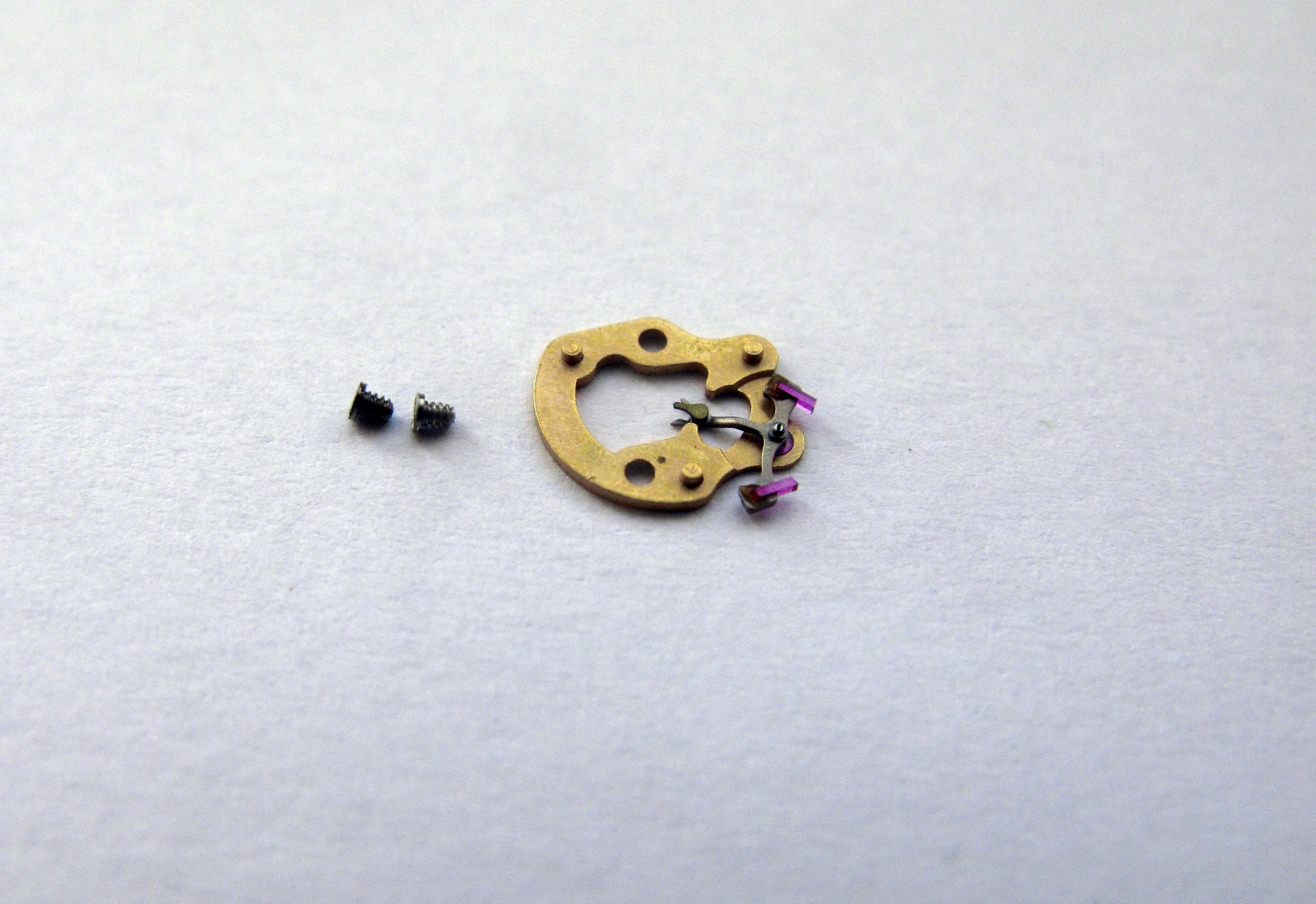The pallet bridge and fork laid on paper next to their two fixing screws.