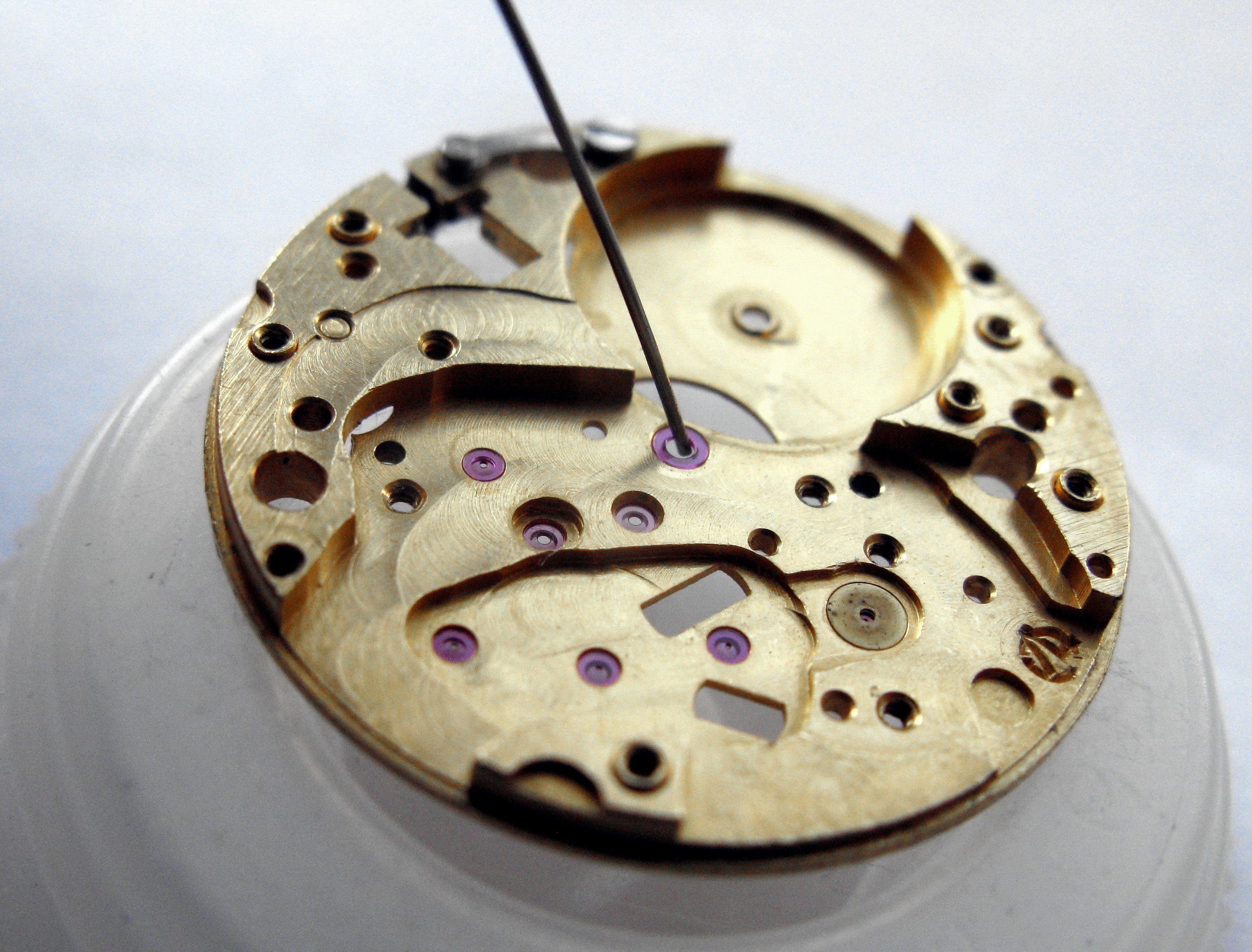 An oiler needle delivering a trace of oil to the central jewel of the mainplate.