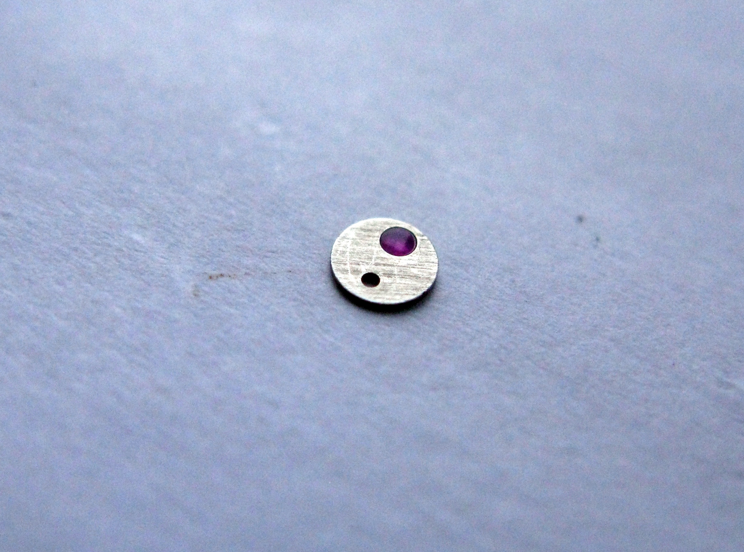 A droplet of oil being applied to the balance cap jewel.