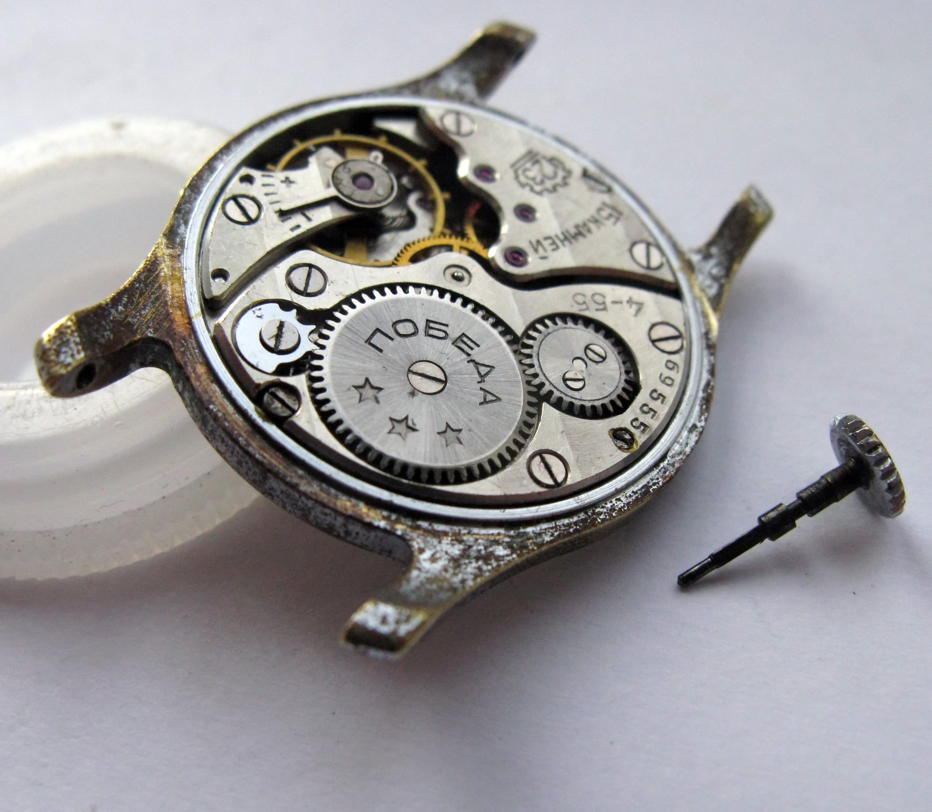 The winding stem withdrawn from the movement, lying beside it.