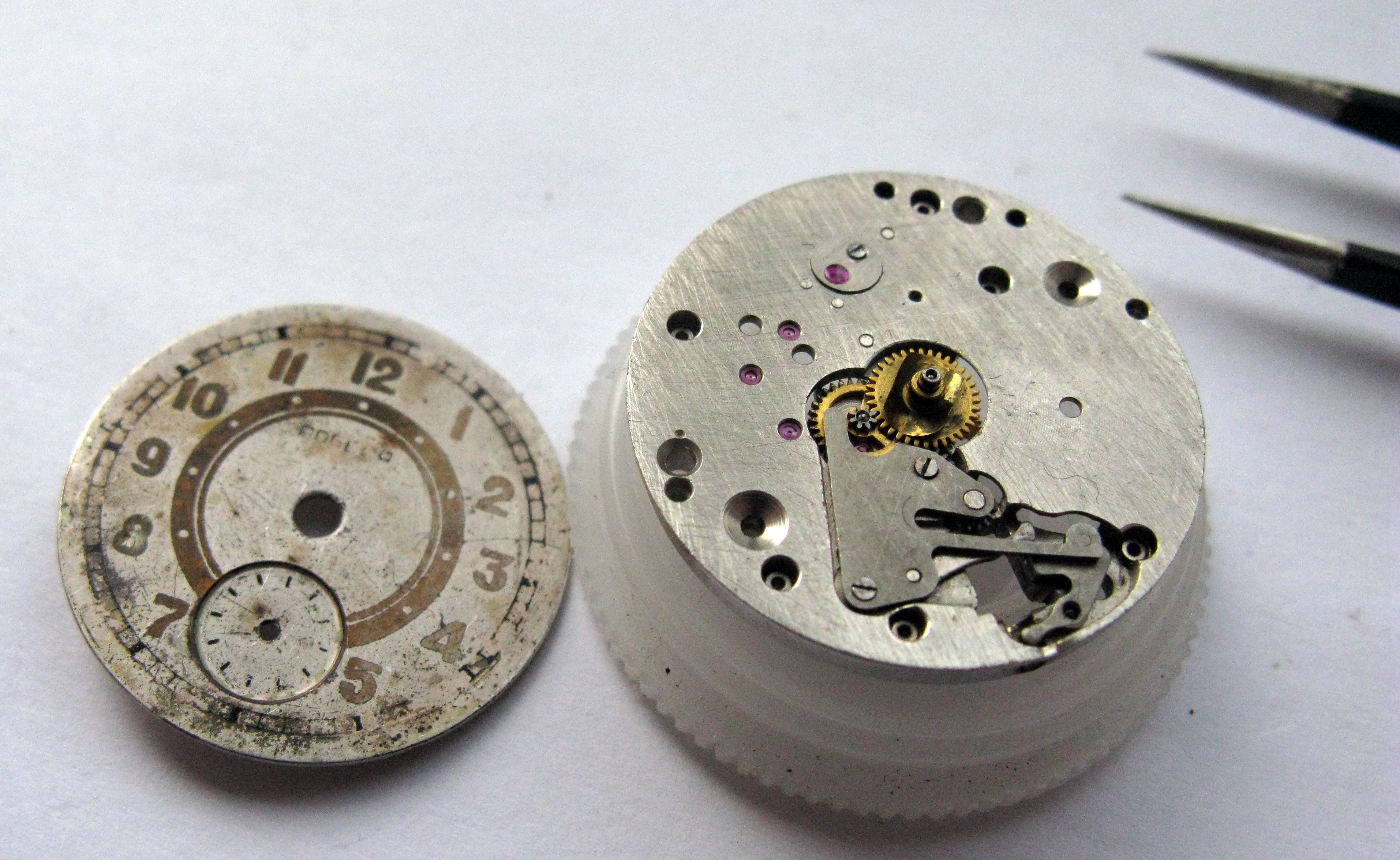 The dial removed and set aside, exposing the slow side of the mainplate with the keyless works.