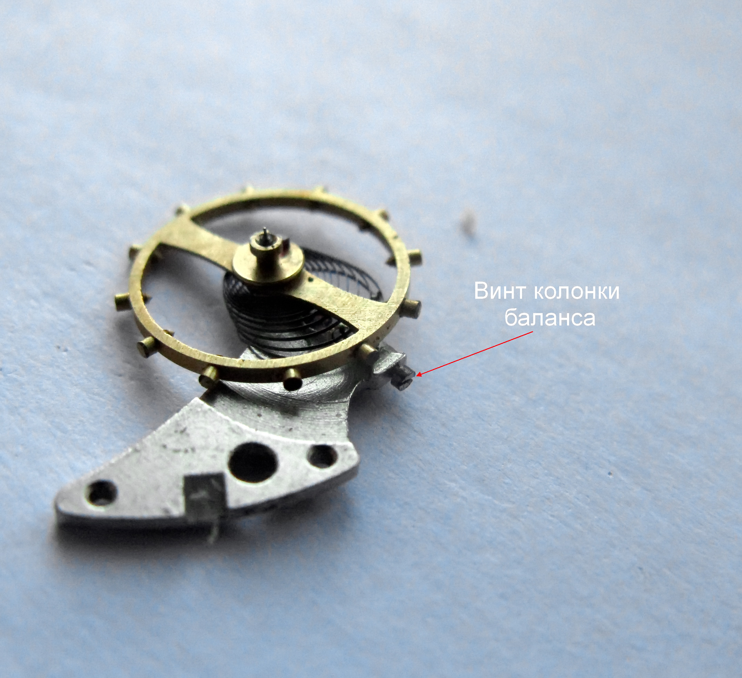 The balance assembly with a red label pointing to the balance-stud screw.
