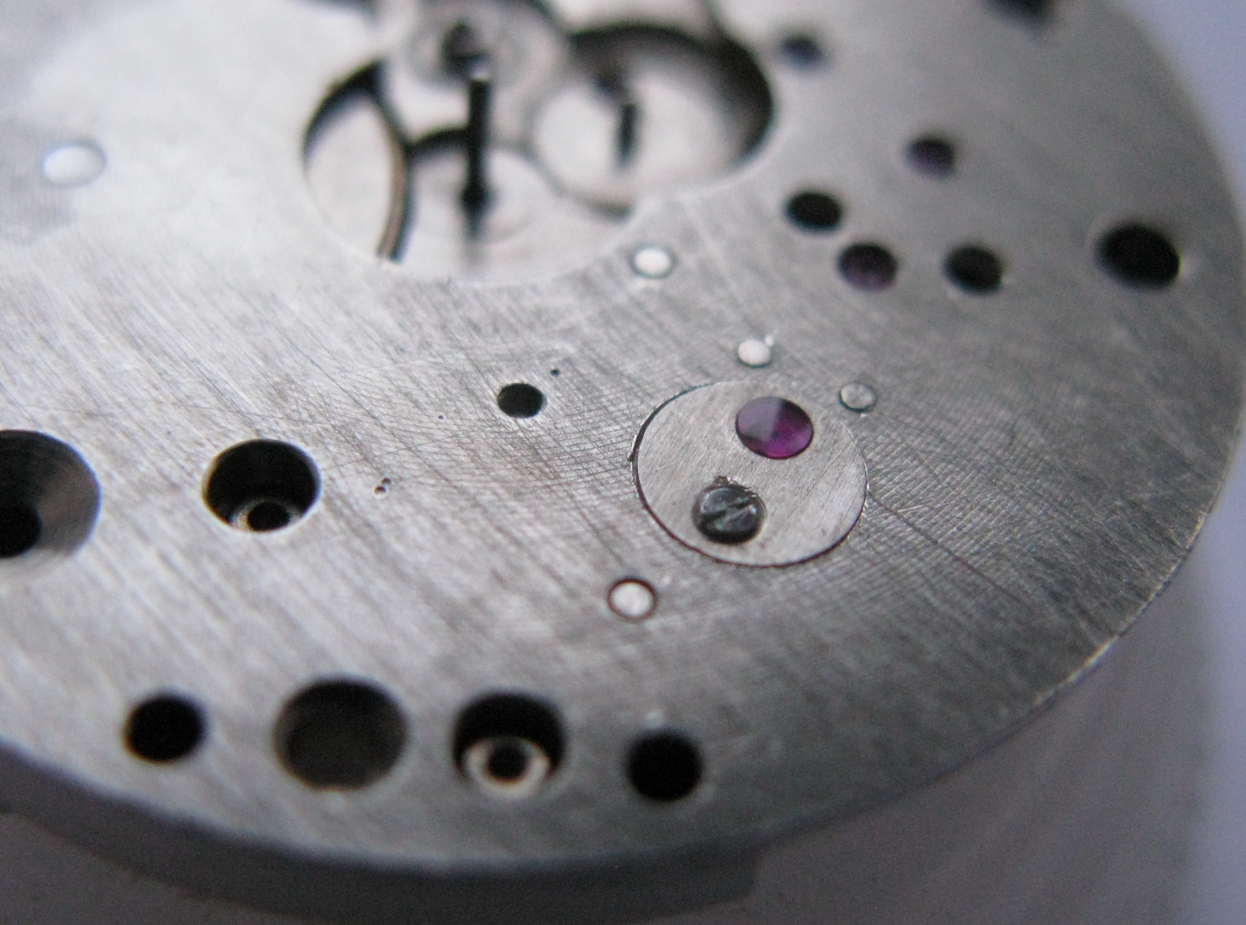 The oiled cap jewel being set onto the mainplate.