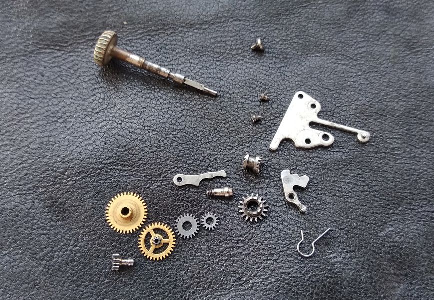 The keyless-works components being lifted out of the dial side of the movement during disassembly