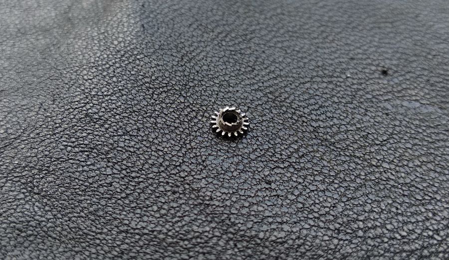 The winding pinion shown face-on, its gear rim around the edge and the saw-tooth clutch ring on its side face both visible