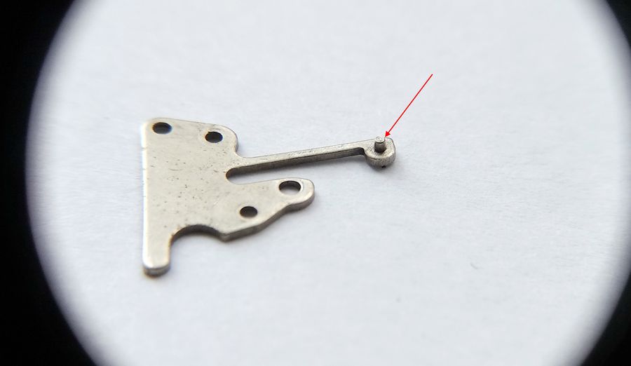 The spring cover of the keyless works with its detent finger indicated by a red arrow