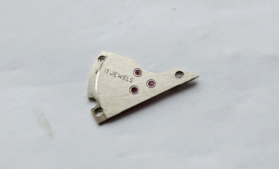 The going-train bridge showing large jewels each ringed by an oil-retaining groove and Latin-script markings