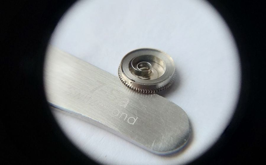 The barrel rim showing a punched dot marker aligned with the protruding sword-shaped spring tang