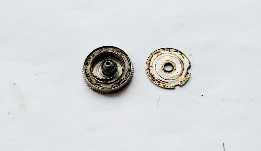 The opened mainspring barrel showing thick, stringy degraded lubricant inside
