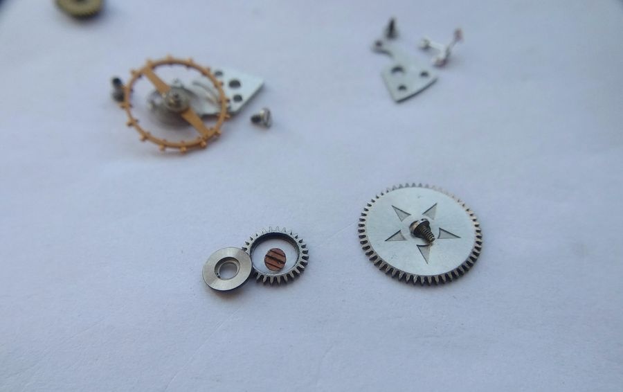 Crown wheel and ratchet wheel from the Raketa 2609B winding system removed and laid out on the work surface