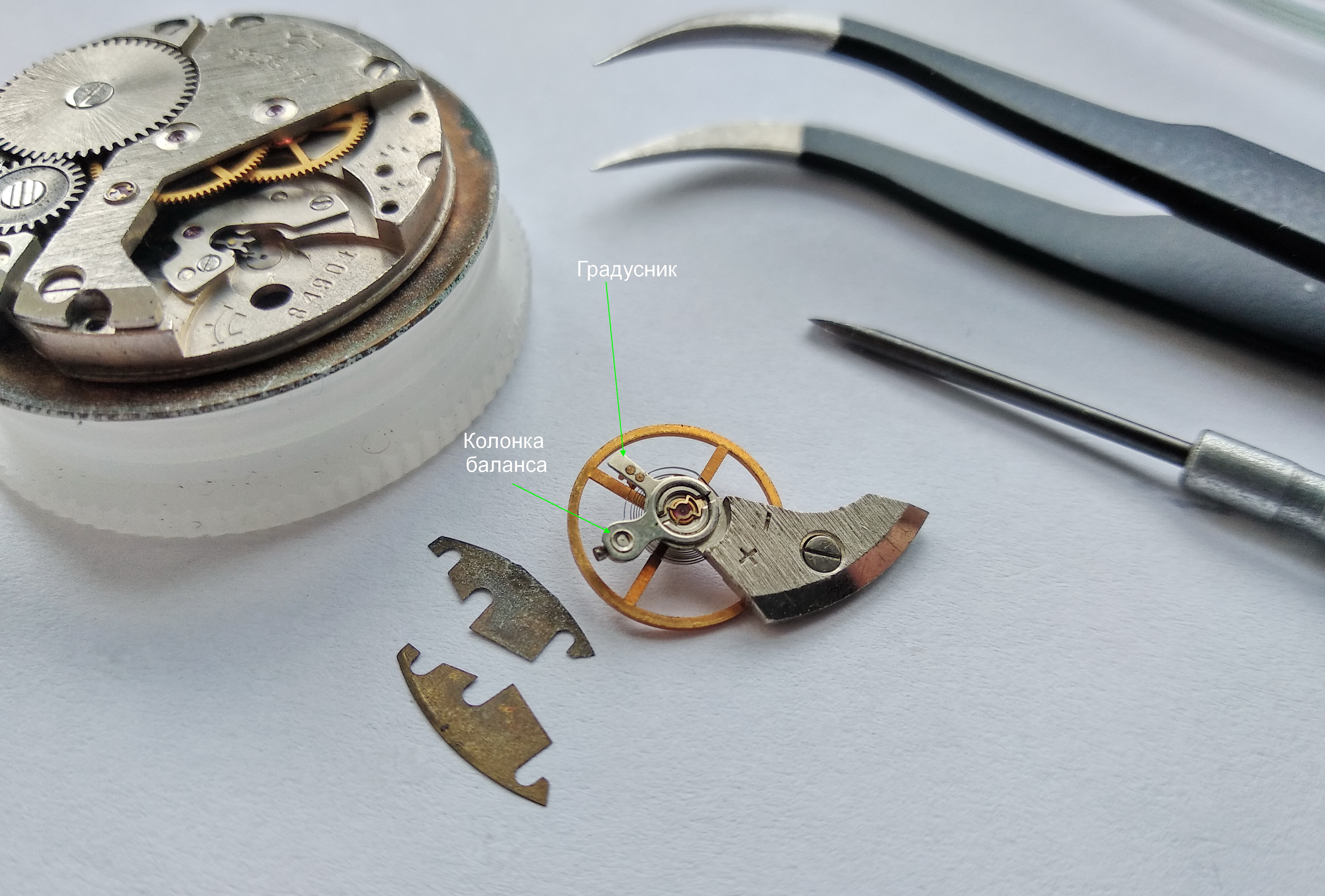 Balance assembly lifted from the movement together with thin shim spacers under its cock