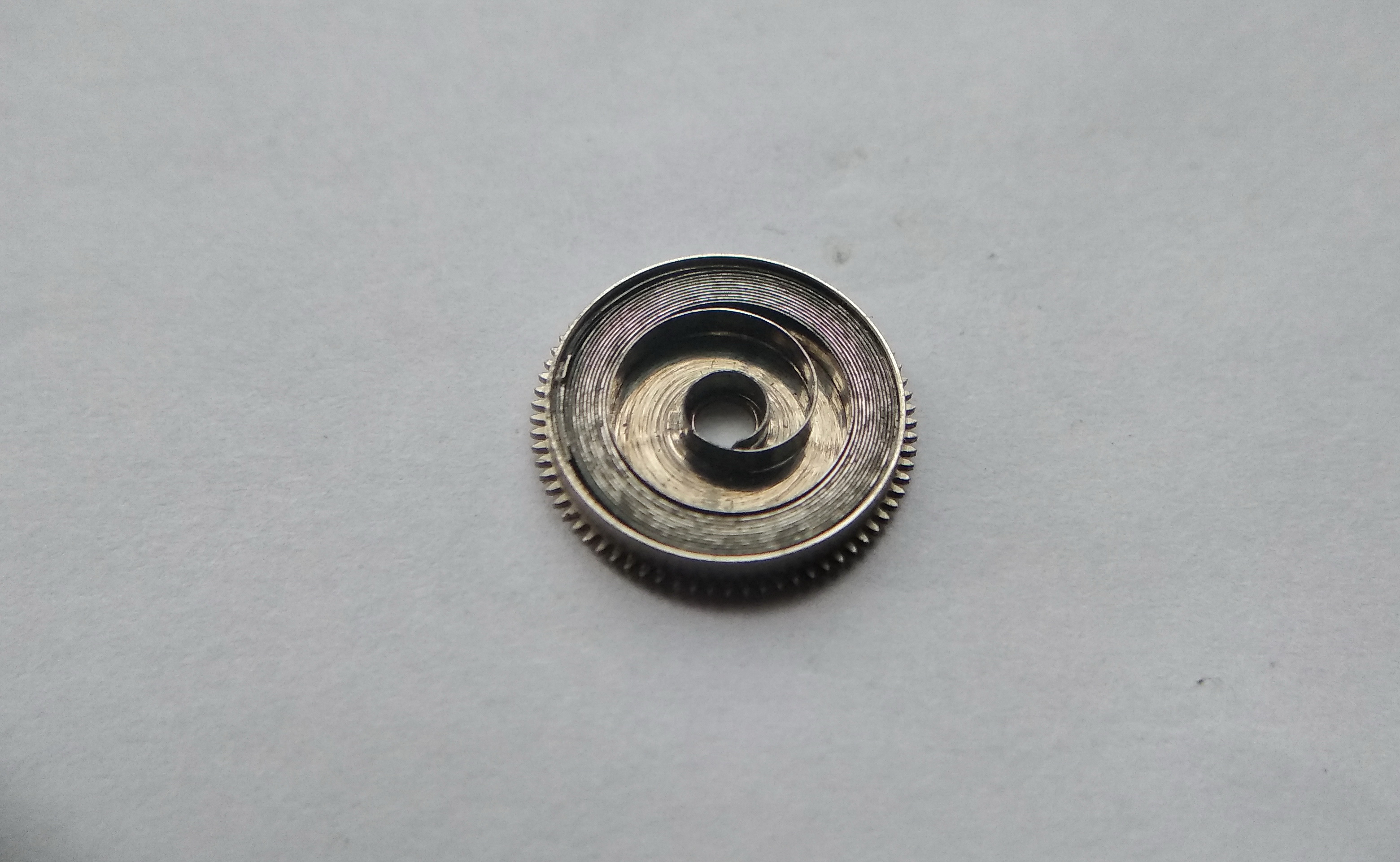 Open barrel with the coiled mainspring inside, its inner loop visible at the center