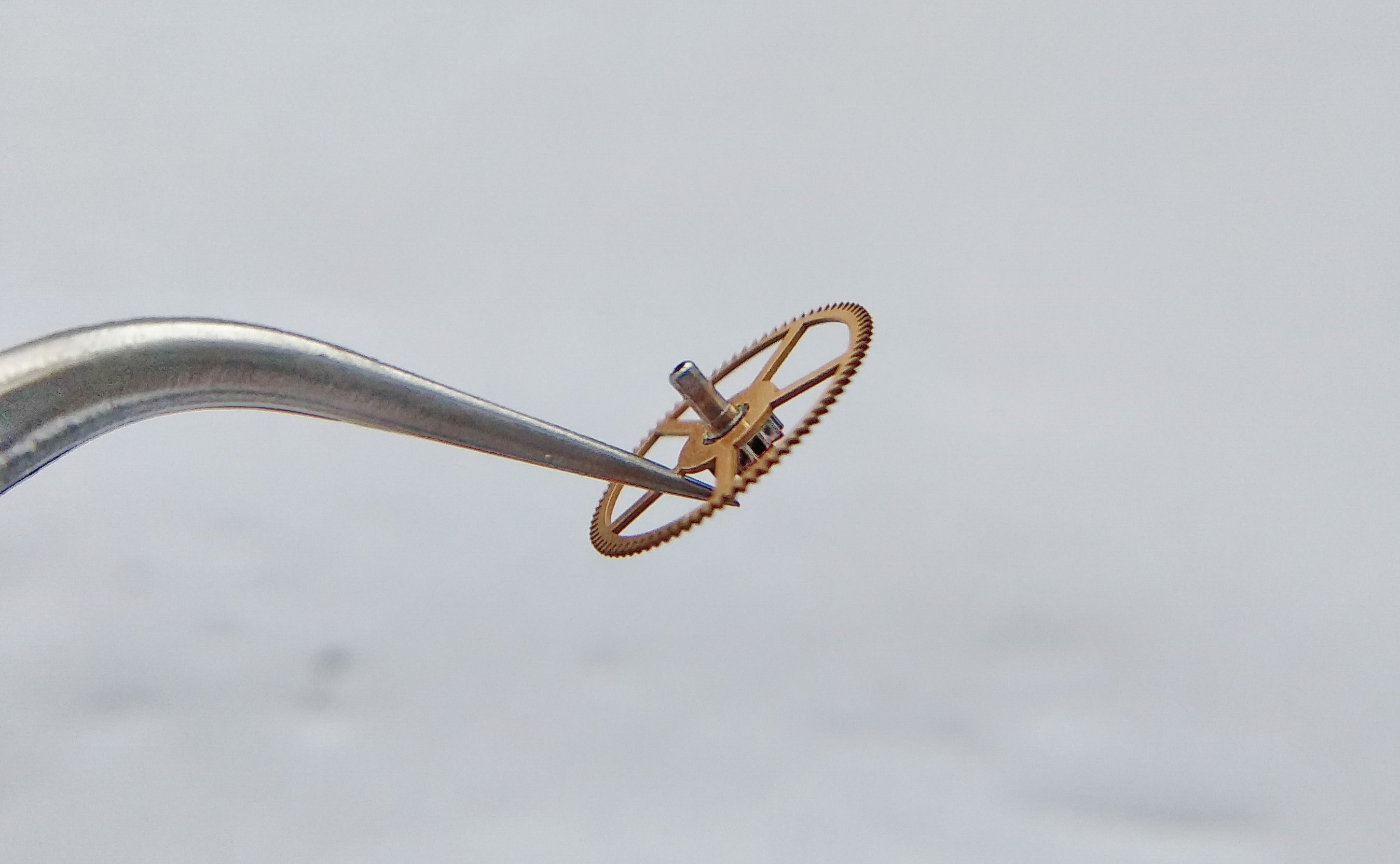Center wheel held by a spoke with tweezers before placement