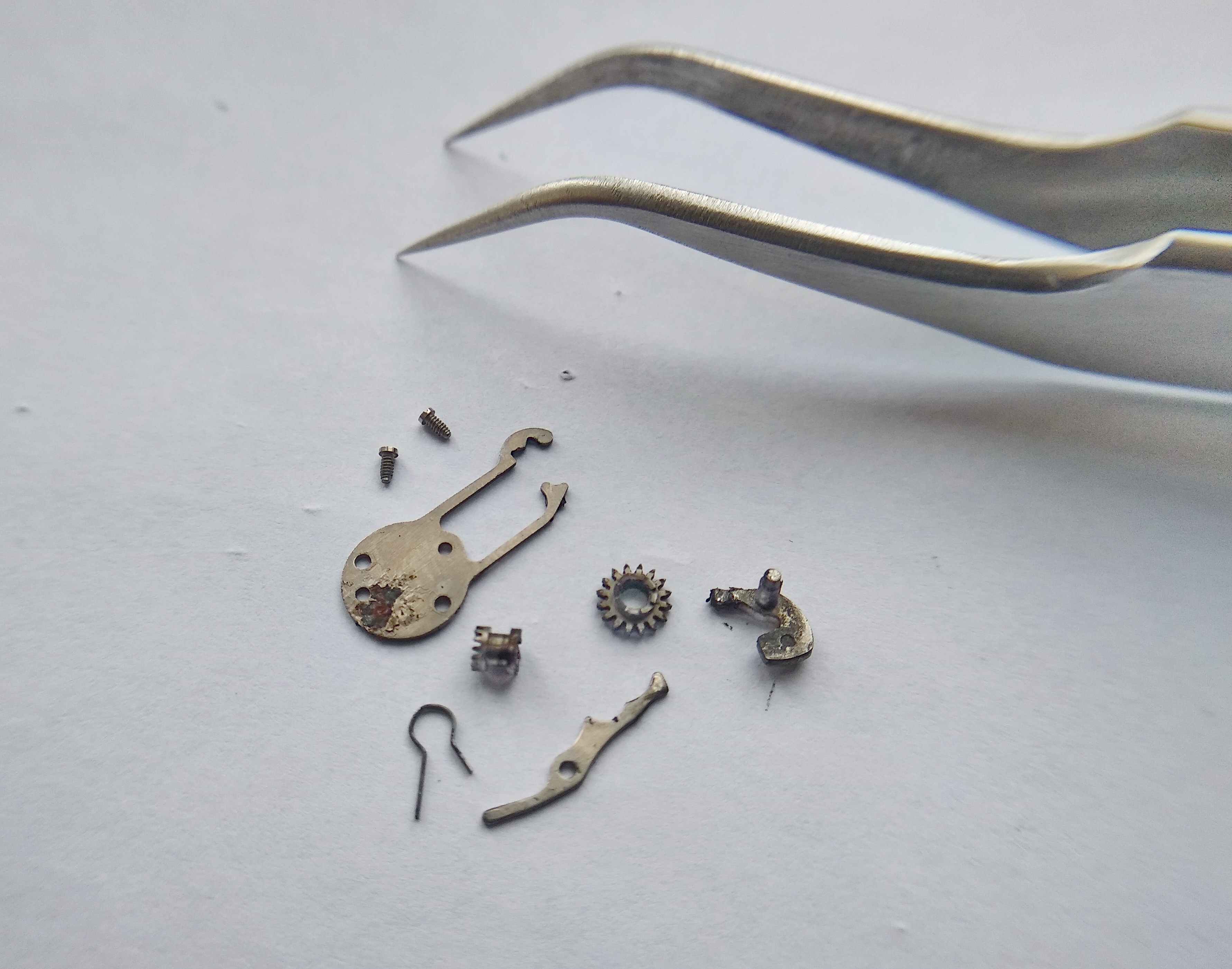 Disassembled keyless works laid out: R-spring, setting levers, castle clutch, and cover spring