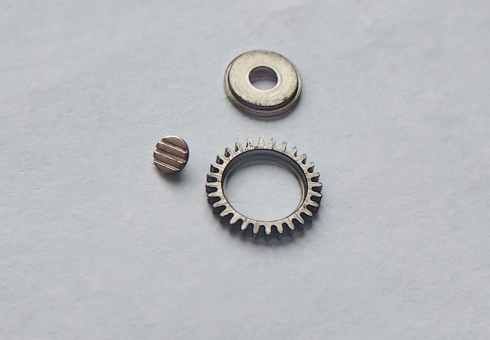 Ratchet wheel screw with three slots marking its left-hand thread