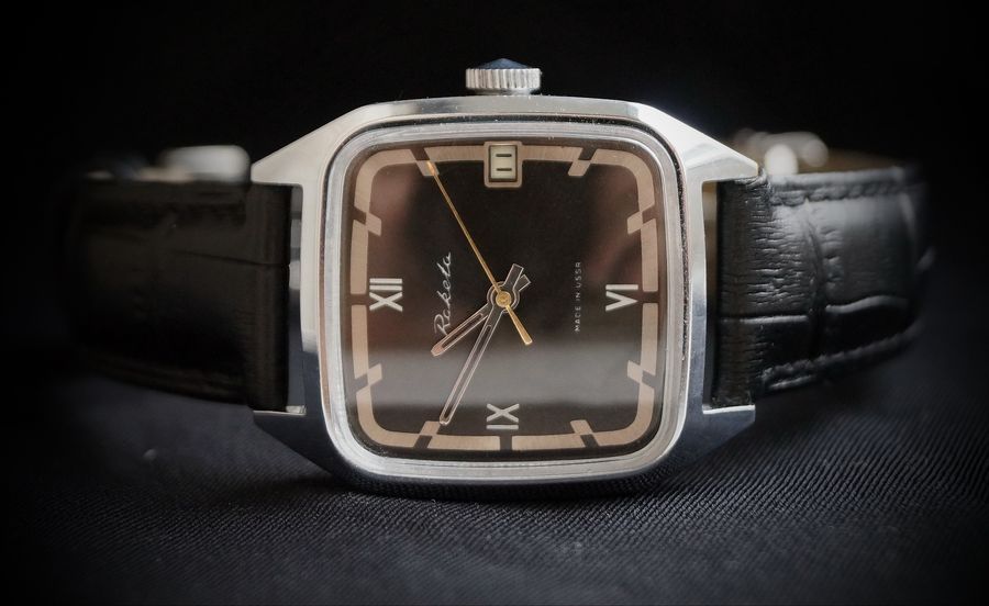 Three-quarter close-up of the chrome version with a dark dial against a black background