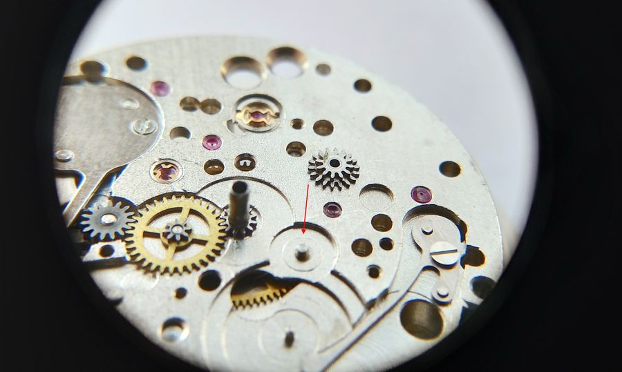 A loupe view of the plate with a red arrow pointing to the arbor seat for the two-tier calendar wheel