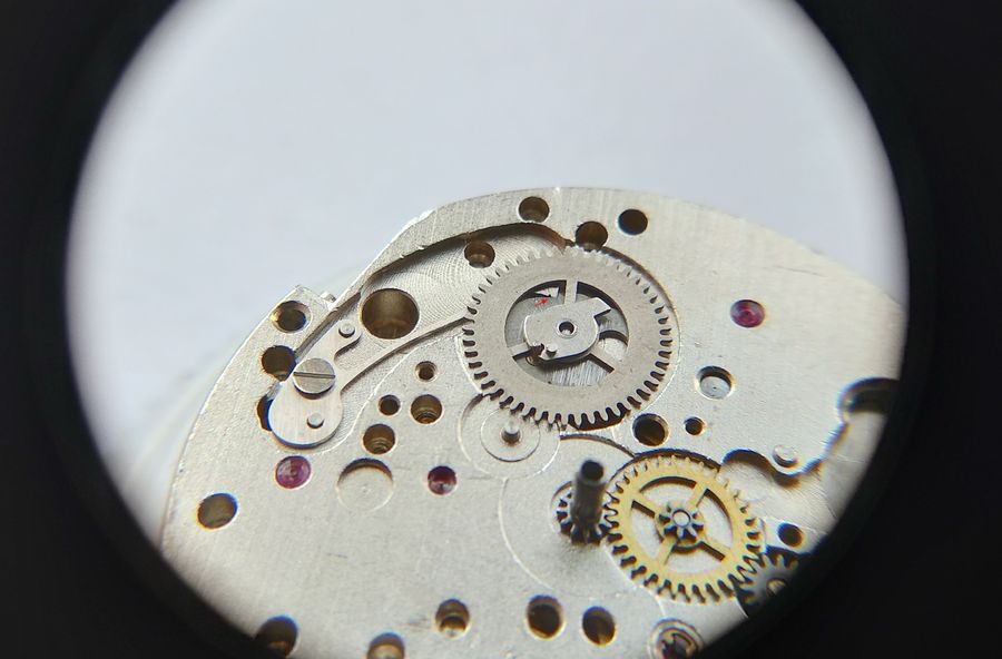 The command wheel being lowered into place with the accumulating spring eased aside by pegwood, a red arrow marking the beak position