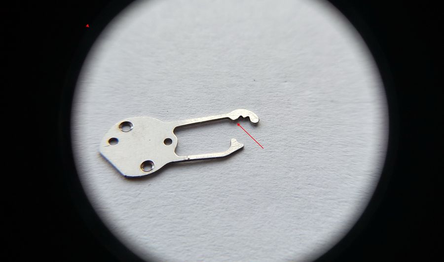 The keyless cover spring held up to show a small protrusion on its edge