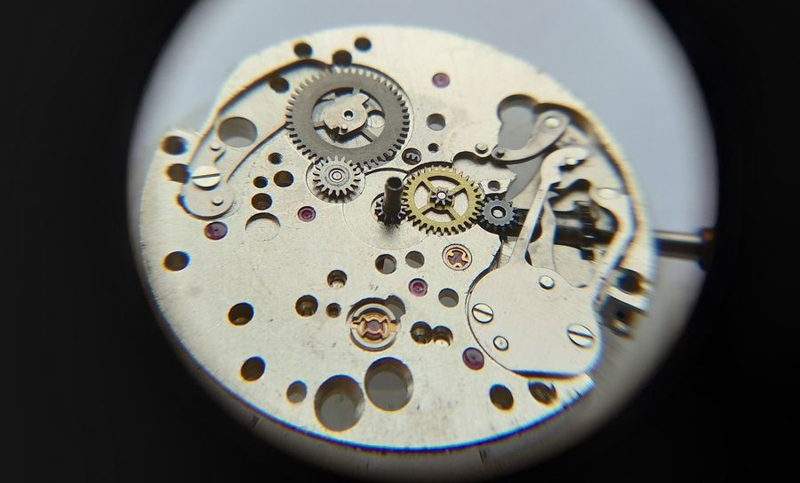 The full calendar mechanism revealed on the plate after the number disc is removed, levers and wheels visible