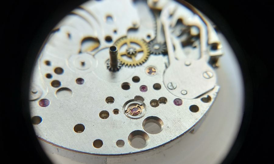 The lyre-shaped shock spring being clipped closed over the cap-jewel setting