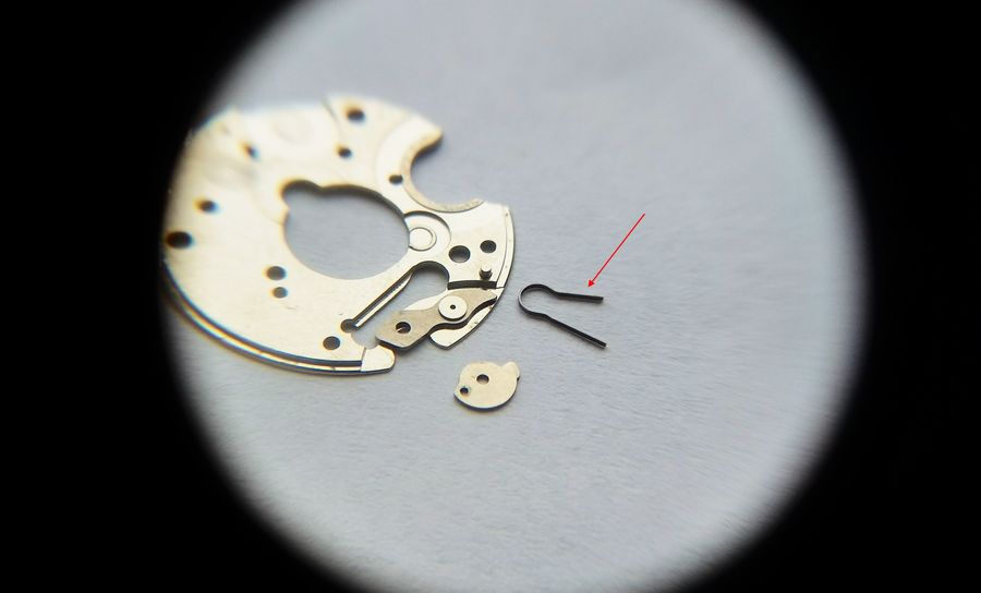 The disassembled calendar bridge with the correction sector and a misshapen R-shaped spring laid out beside it
