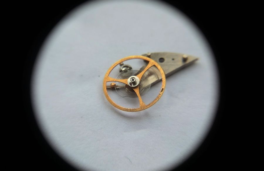 Another angled magnified view of the gilt three-arm balance wheel and hairspring