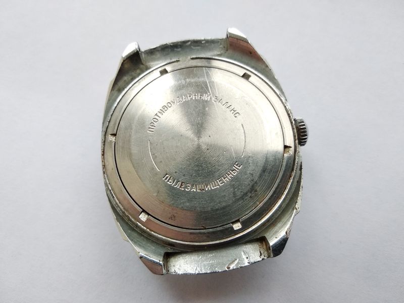 The watch case back retained by a figured screw-down ring, with penetrating fluid applied to the seam