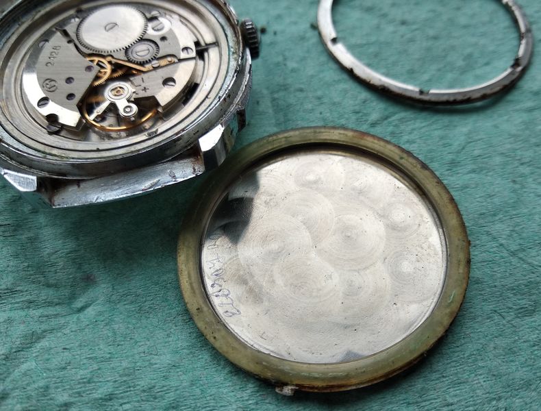 The inside of the case back showing a hardened gasket and an engraved repairer's signature