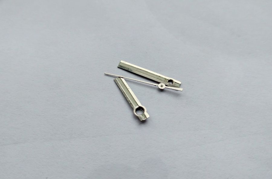 The watch hands removed and lying on the bench