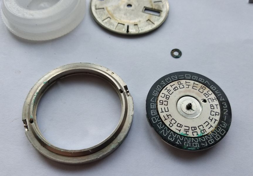 The movement separated from its carrying ring, with the stamped pan-shaped dial alongside