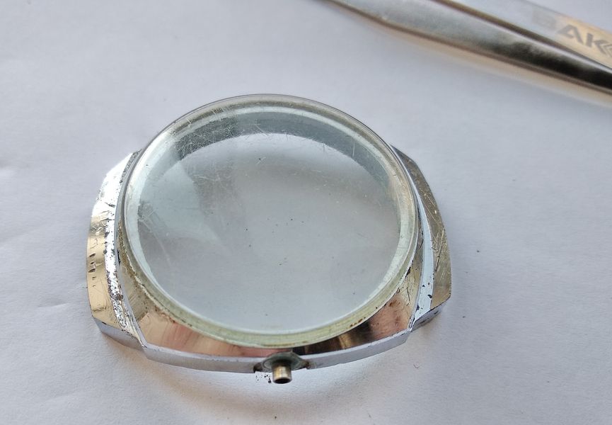 The exterior of the watch case and its scratched crystal before restoration