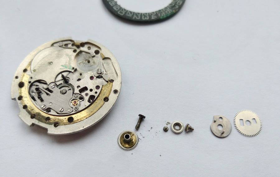 The disassembled calendar drive: hour wheel, cannon pinion, two-tier wheel and the eccentric with two shifting fingers of different heights