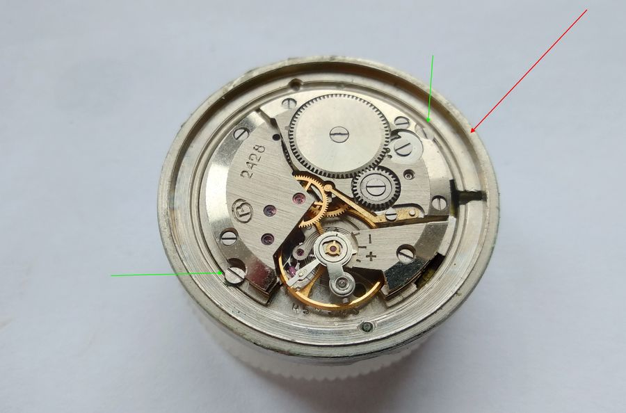 The two screws securing the caliber within its ring indicated by green arrows