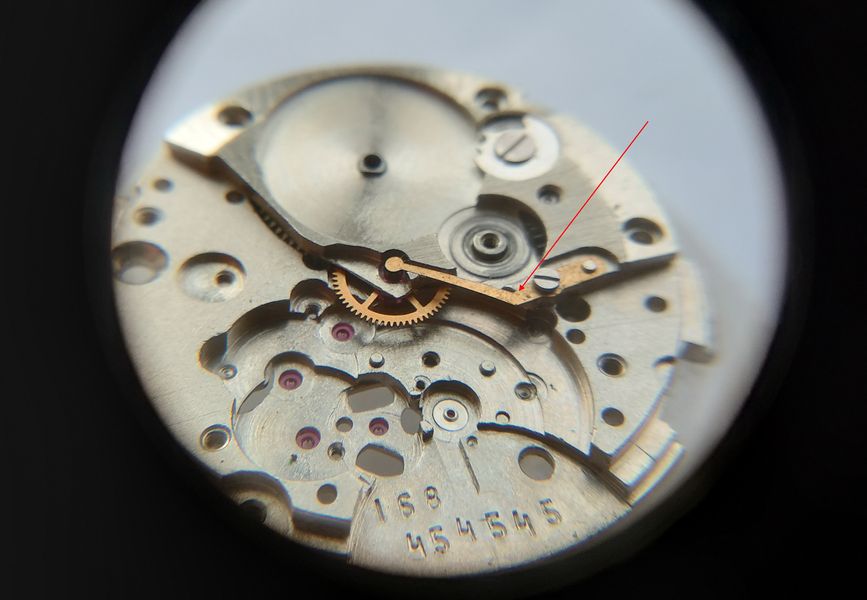 The hook-shaped lever that supports the seconds pinion, before removal
