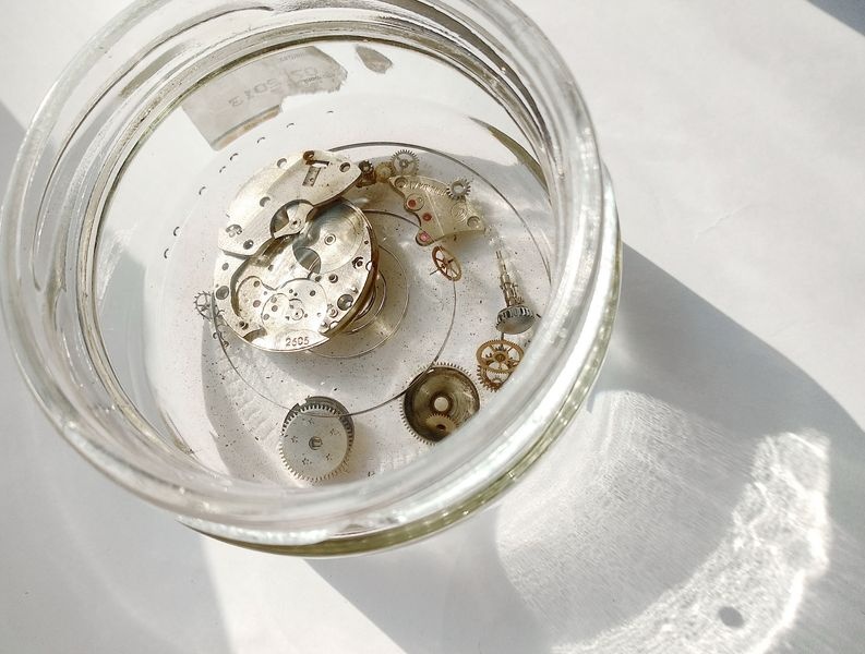 Vostok 2605 all movement components submerged in glass jar with benzine cleaning solvent on balcony