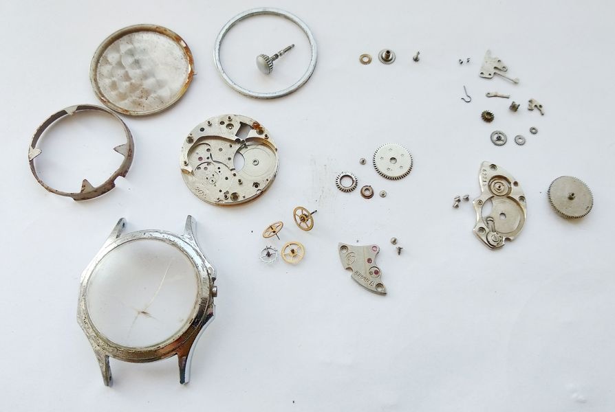 All Vostok 2605 components fully disassembled and laid out on workbench in groups