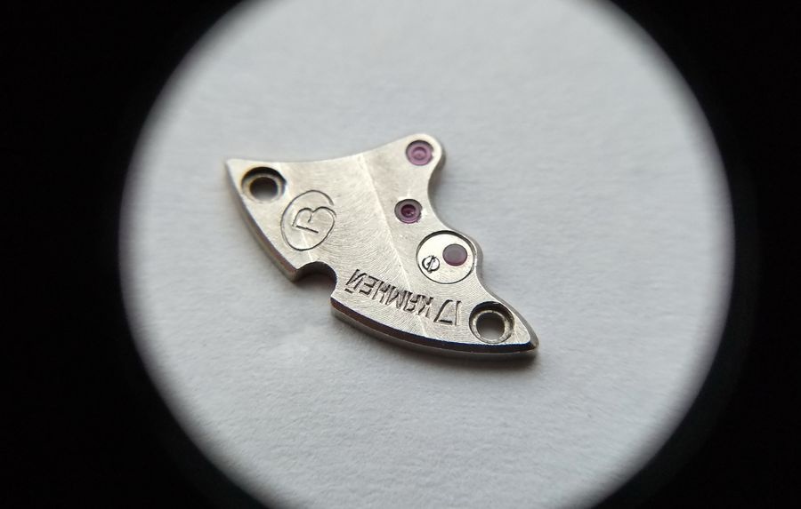Vostok 2605 gear train bridge through loupe showing overlay jewel reinstalled with dark circular ring confirming lubrication and parallelism