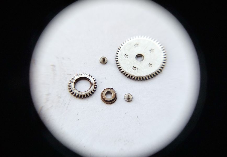 Vostok 2605 winding wheel system disassembled through loupe showing winding train components