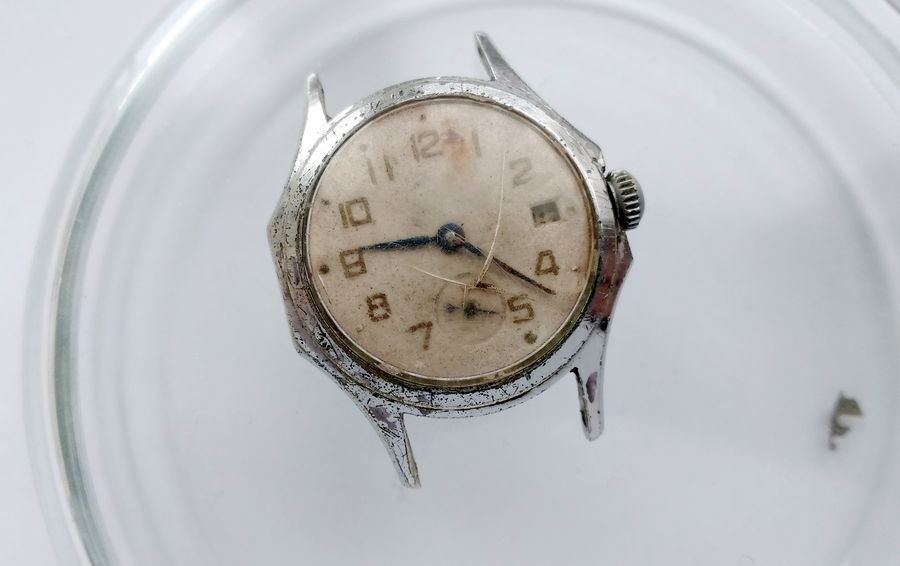 Vostok watch front view showing broken crystal bleached numerals rust at case seams and date aperture with something visible inside