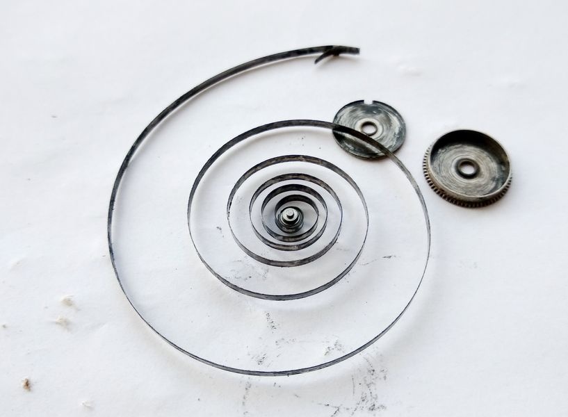 Vostok 2605 mainspring fully extended alongside barrel body and cover showing spring length and condition