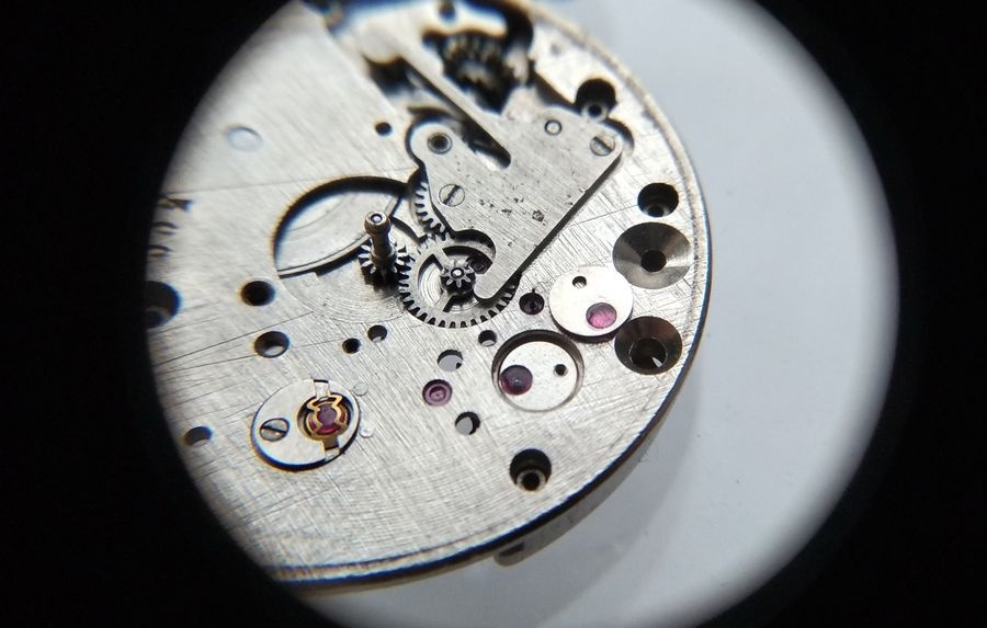 Vostok 2605 dial side through loupe with keyless works spring cover installed and escape wheel overlay jewel being serviced with MBP-12