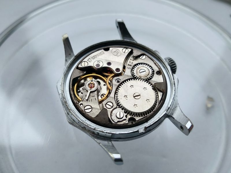 Vostok 2605 assembled movement installed in case with caseback open showing bridge side with Geneva stripes going train and balance