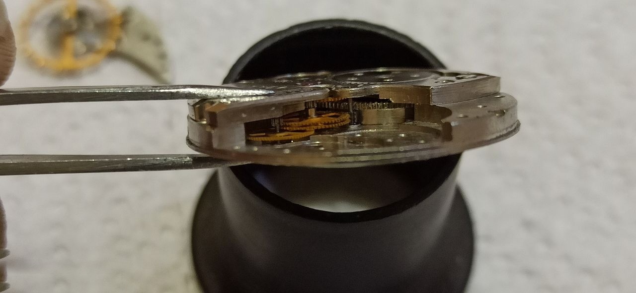 Side profile of the movement held in tweezers on a stand