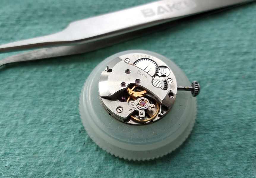 The cleaned silvered dial being refitted onto the running movement